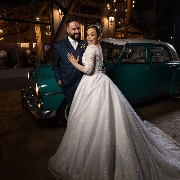 Casal ao lado de carro antigo, noivo de terno azul-marinho